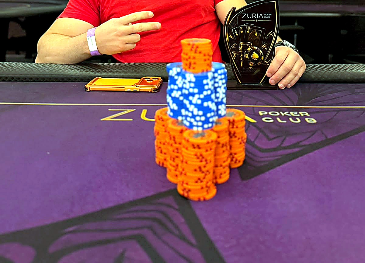 Trofeu do Zuria Poker Club com torres de fichas na mesa roxa e dourada da casa