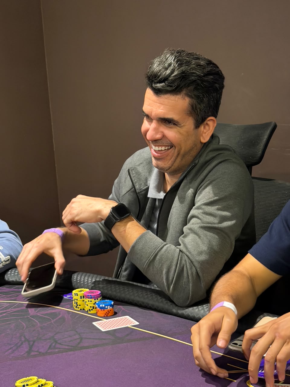 Jogador rindo durante uma mao na mesa de poker do clube
