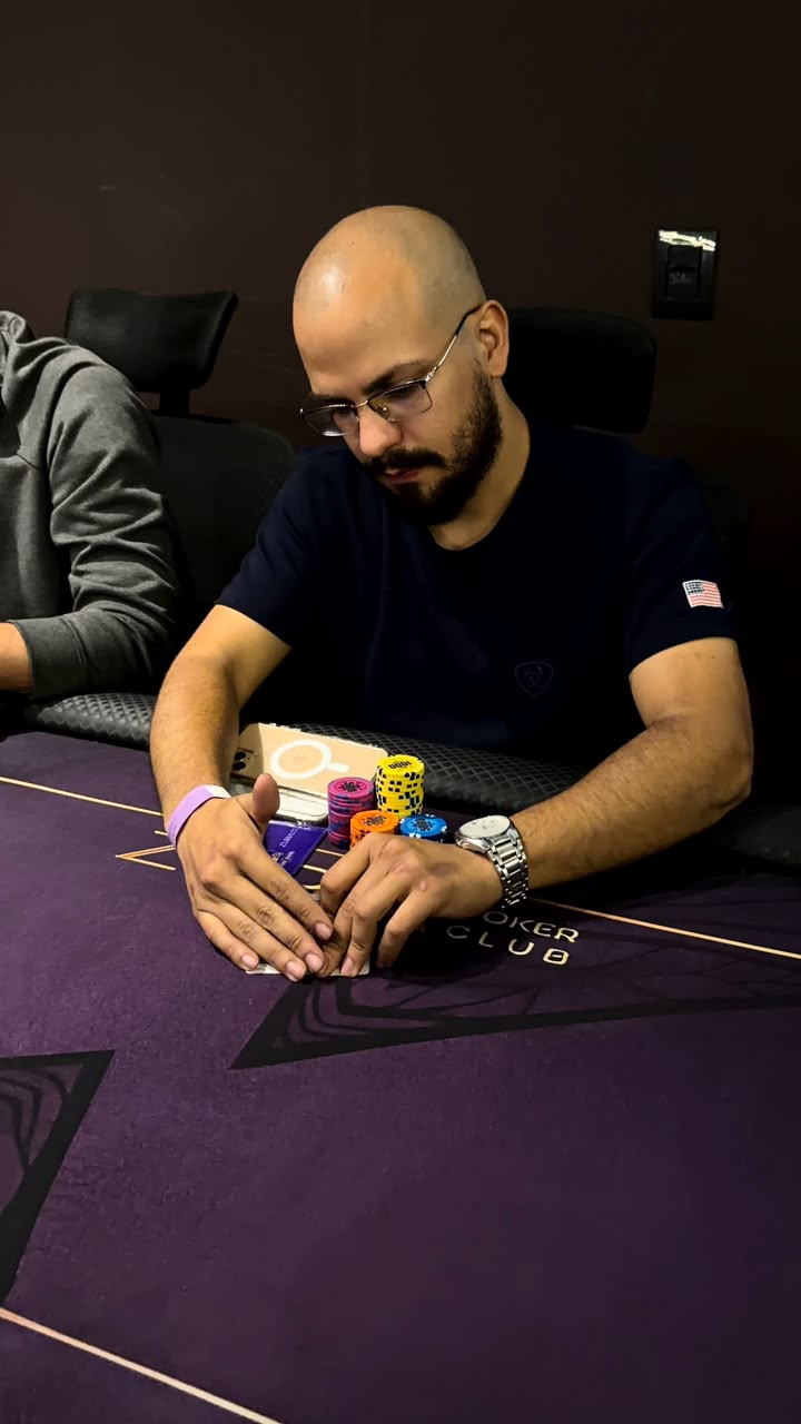 Maos de um jogador com fichas sobre o pano roxo com o logo Zuria Poker Club