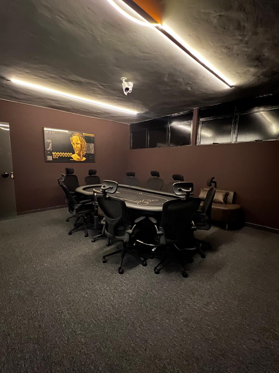 Sala VIP do Zuria Poker Club: mesa de poker profissional de nove lugares com poltronas e o quadro dourado na parede